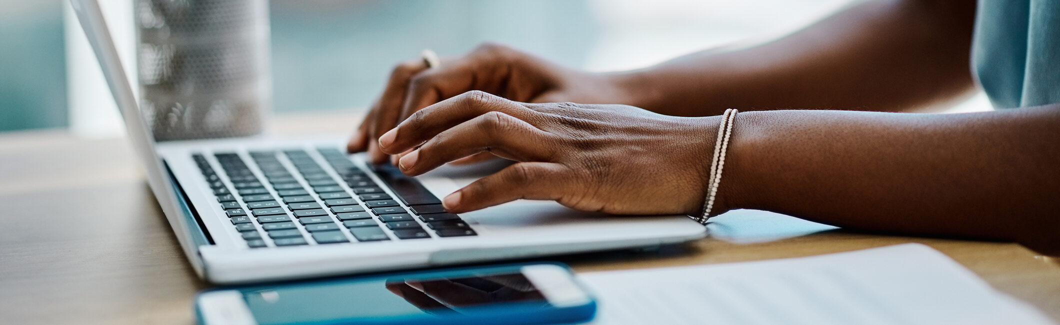 Closeup of a black businesswoman typing on a laptop keyboard in an office alone