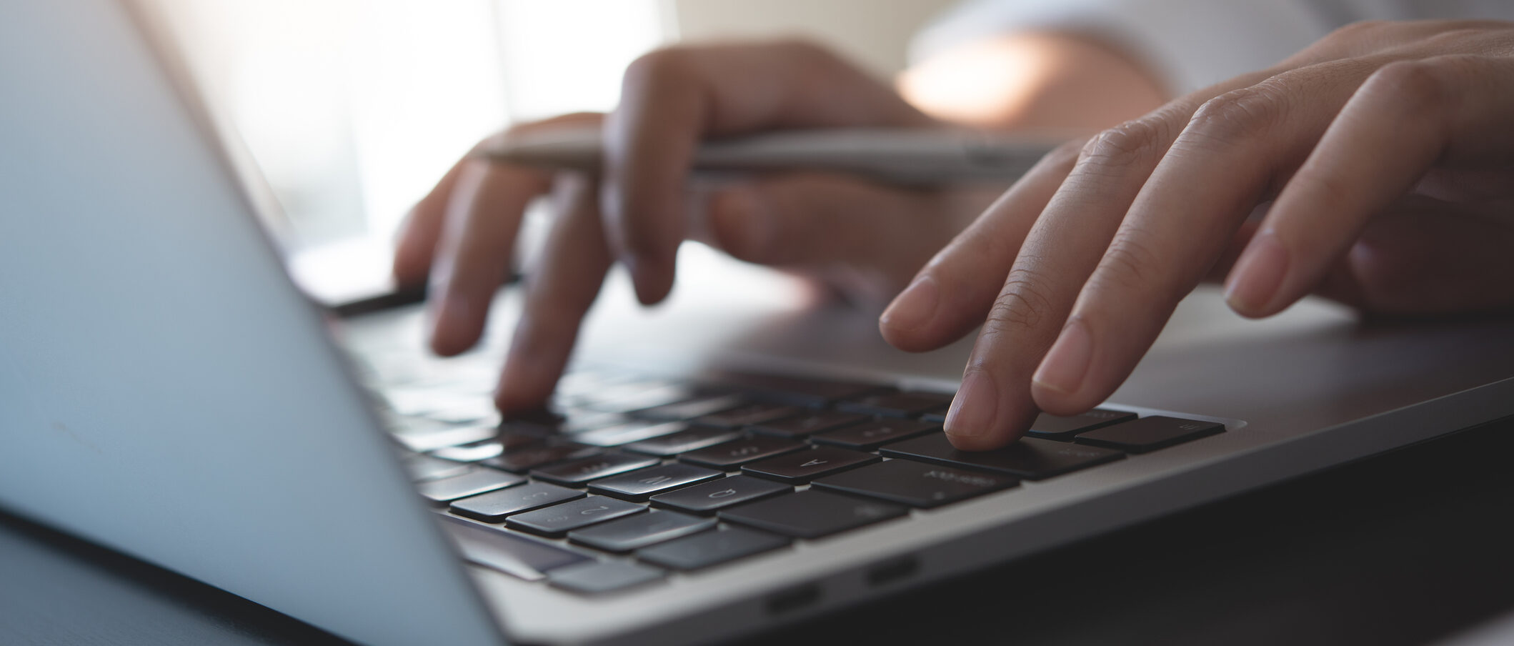 Closeup of woman hand typing, searching the information on laptop computer with a pen and notebook on office table, online working, internet networking, e-learning, digital education concept
