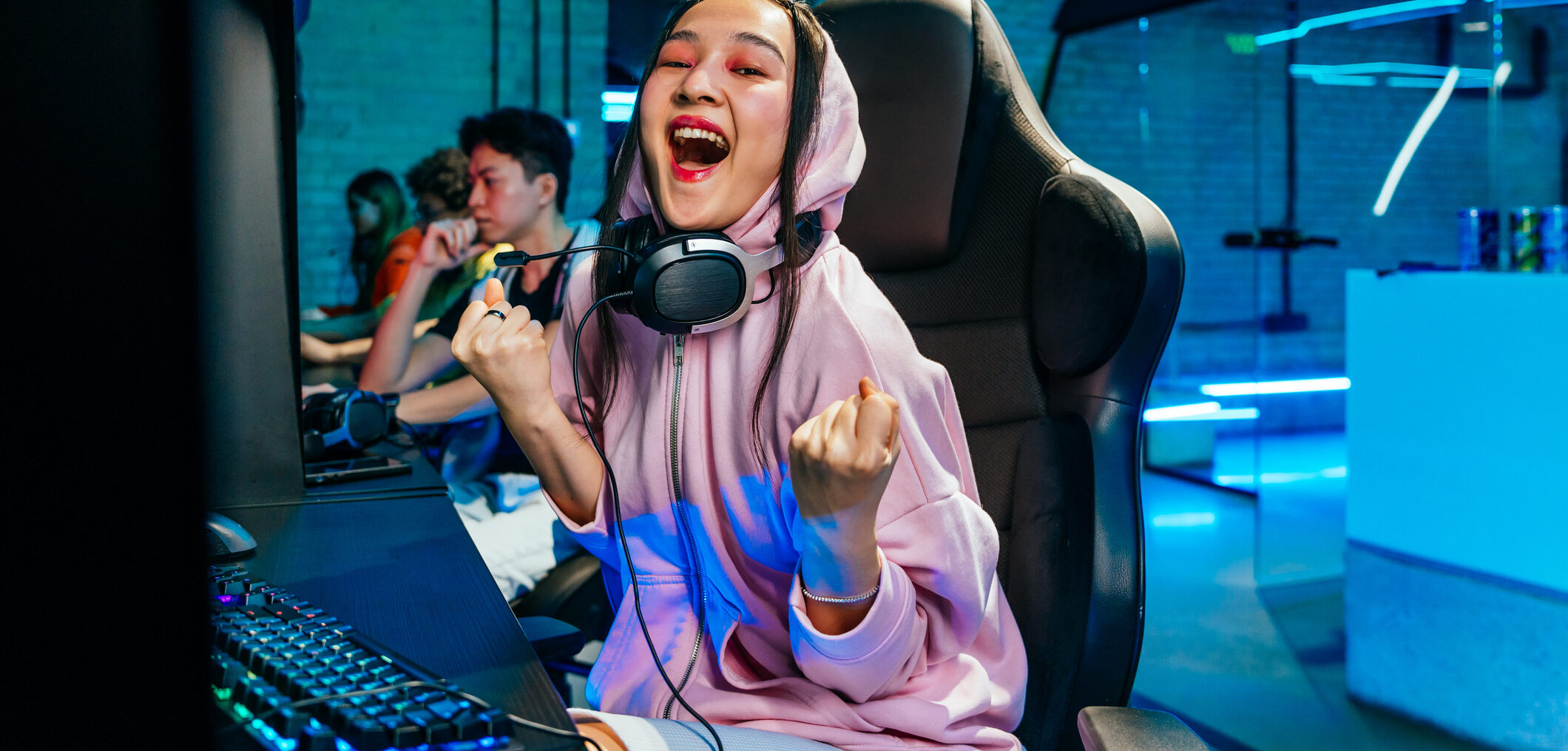 Beautiful young asian woman playing videogames in a internet cafe - Videogamer having fun playing e-sports at computer videogame console