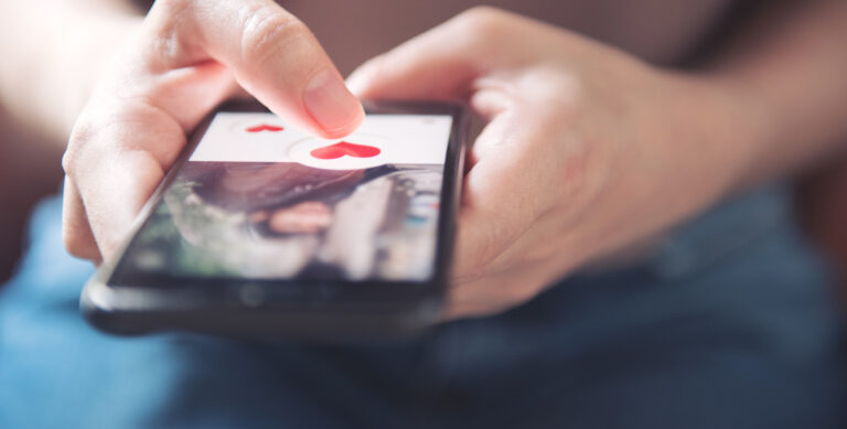 Finger of woman pushing heart icon on screen in mobile smartphone application. Online dating app, valentine's day concept.