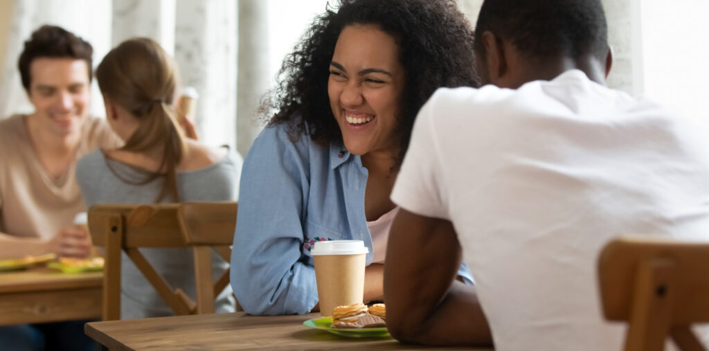 Happy young mixed race girl attending speed dating, getting acquainted with interesting people, joking, laughing, having fun. Millennial woman meeting black friend, enjoying spending time together.
