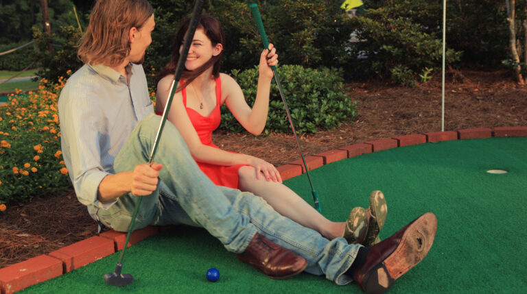 Happy young couple on a miniature golf date.